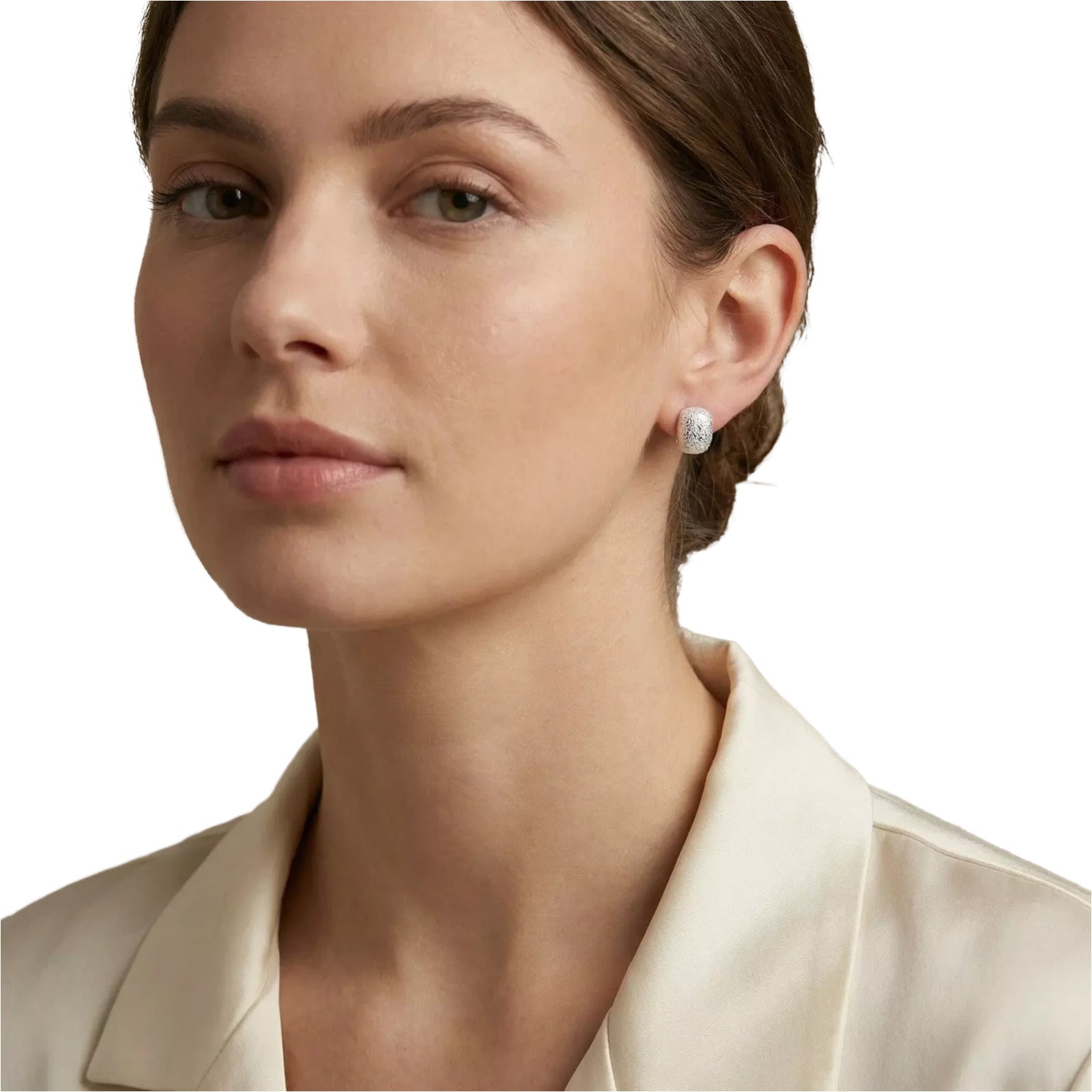 A close-up portrait of a woman wearing a beige blazer and diamond stud earrings.