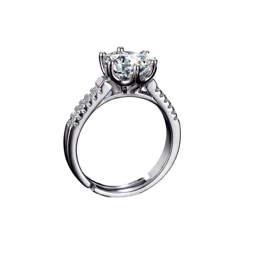 A close-up of a diamond engagement ring with a large central diamond surrounded by smaller diamonds on either side, set in a silver band, against a dark background.