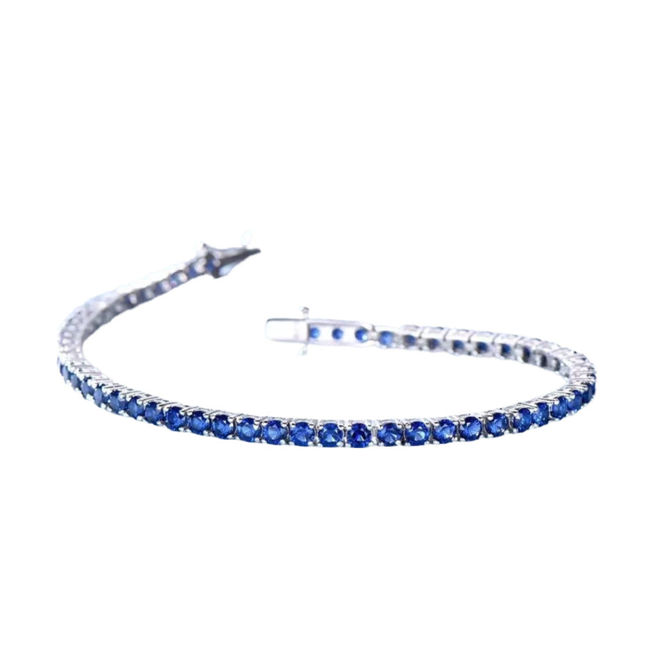 A silver bracelet with blue sapphires arranged in a row.